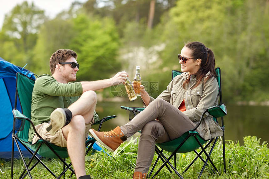 野营,旅游,徒步旅行人们的快乐的夫妇营地帐篷里碰啤酒瓶图片