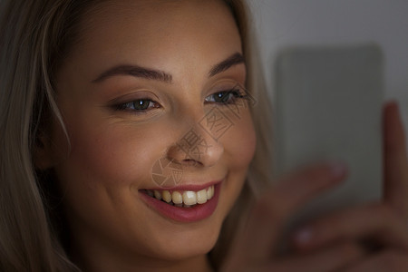 技术,互联网,沟通人的快乐的微笑轻妇女家里的智能手机短信晚上图片