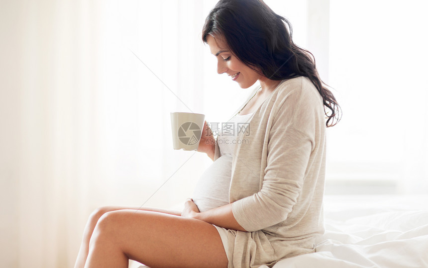 怀孕,饮料,休息,人期望的快乐的孕妇用杯子喝茶坐家里的卧室床上图片
