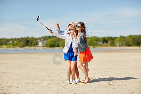 暑假,假期,旅行,技术人的群微笑的轻女海滩上自拍杆上用智能手机拍照图片