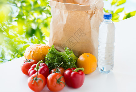 烹饪,饮食,素食健康饮食纸袋与新鲜成熟多汁的蔬菜水瓶桌子上的绿色自然背景图片
