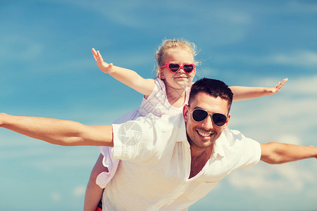 家庭,旅行,度假,收养人们的快乐的男人戴太阳镜的小女孩蓝天背景下玩得很开心图片