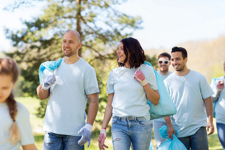 志愿服务慈善清洁人与生态群带垃圾袋公园散步的快乐志愿者背景图片