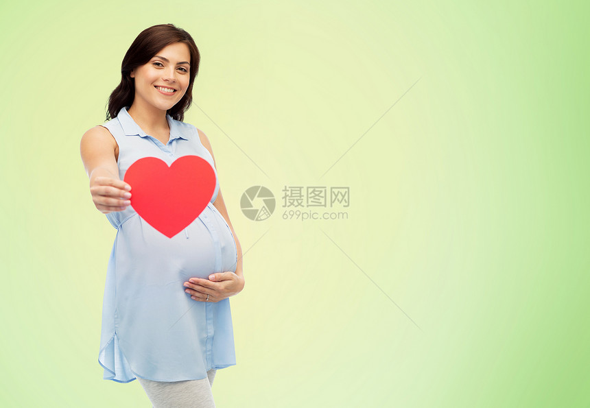 怀孕,爱,人期望的快乐的孕妇,红色的心形触摸她的肚子绿色的自然背景图片