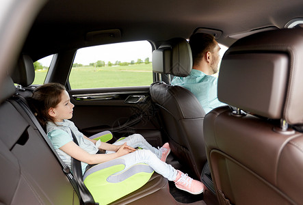 家庭,交通,公路旅行人的快乐的小女孩安全的座位上开车她的父亲图片