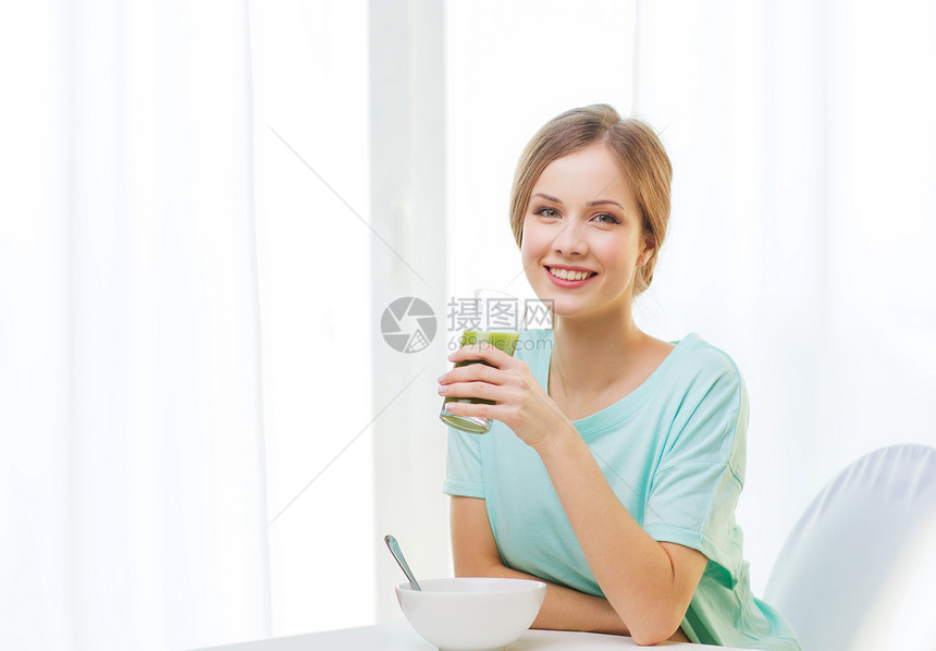 健康的生活方式微笑快乐的女人家里吃早餐,喝绿色果汁冰沙快乐的女人家吃早餐图片