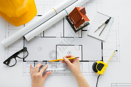 商业建筑建筑建筑人的用尺子铅笔测量客厅蓝图密切建筑师的手背景图片