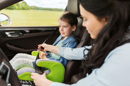 家庭,交通,道路旅行人们的快乐的女人系着孩子的安全安全带车里图片