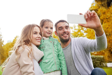家庭,童,技术人的快乐的父亲,母亲小女儿秋季公园用智能手机自拍图片