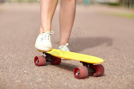 立场滑板,休闲,极限运动人的近十几岁的女孩腿骑短现代巡洋舰滑板路上背景