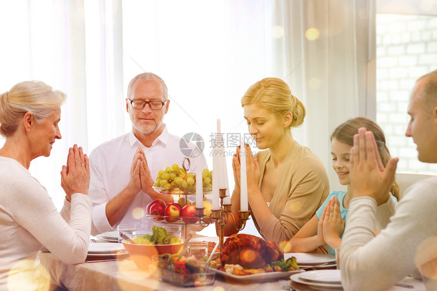 家庭,假期,世代人的微笑的家庭家里吃饭祈祷图片