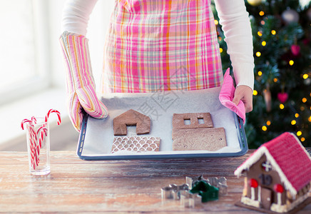 假期,诞节,烘焙糖果特写的女人着平底锅与姜饼屋的细节家里图片