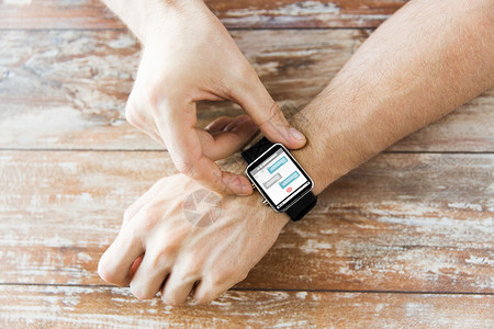 腕表手表详情商业,现代技术,社交网络,沟通人的密切的男手智能手表与信屏幕上的木制桌子设计图片
