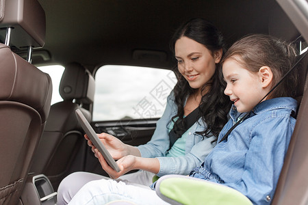 家庭,交通,公路旅行,旅行人的快乐的女人小女儿与平板电脑电脑汽车上驾驶图片