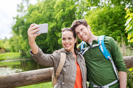 旅行,徒步旅行,背包,旅游人的微笑夫妇与背包采取自拍智能手机自然界图片