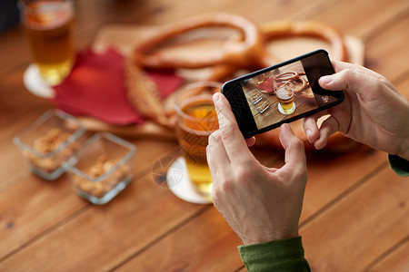 人技术与智能手机亲密的手,想象啤酒椒盐卷饼酒吧酒吧用智能手机特写啤酒图片