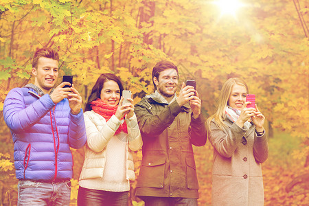 季节,人,技术友谊的群微笑的朋友与智能手机拍照玩增强现实游戏秋季公园图片