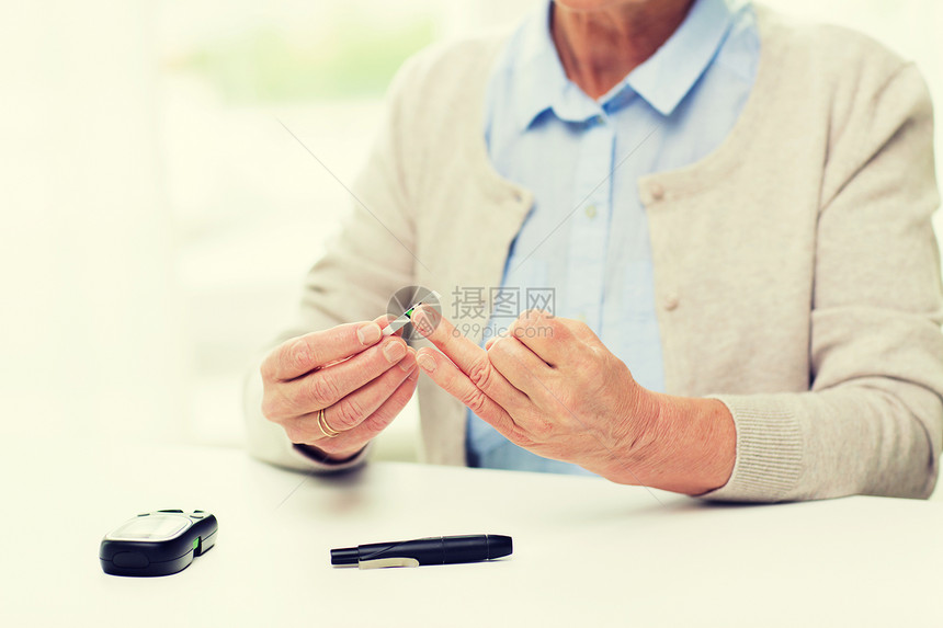 老人在家使用血糖仪检测血糖水平图片