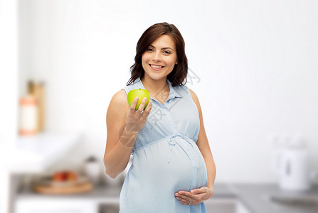 怀孕,健康饮食,食物人的快乐的孕妇着绿色的苹果家里的厨房背景图片