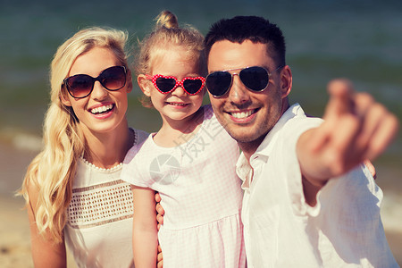 旅行,度假,收养人们的快乐的家庭与小女孩戴着太阳镜夏天的海滩上指指点点图片