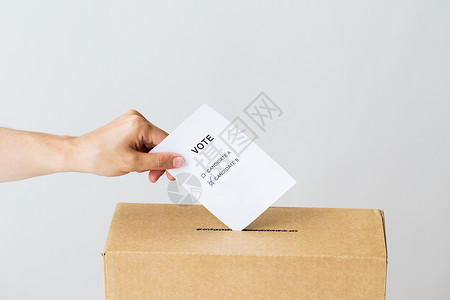 投票公民权利人民男手把两名候选人的投票放入选举的投票箱背景图片
