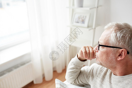 老,生活方式人们的亲密的老人戴着眼镜看着家里的窗户图片