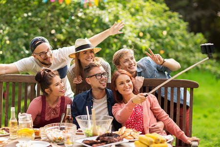 休闲,派,技术,人假期的快乐的朋友拍照与智能手机自拍棒聚会晚餐夏季花园聚会图片