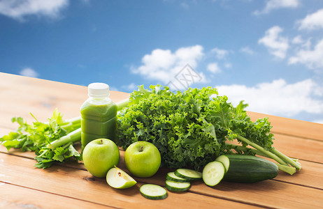 健康饮食,食物,饮食素食瓶子与绿色果汁,水果蔬菜木制桌子上的蓝天背景图片