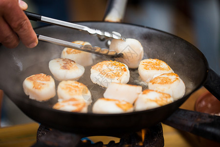 烹饪,亚洲厨房,销售海洋食品亚洲街头市场上,用钳子煎扇贝来烹饪背景图片
