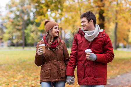 桃花散步喝饮料爱,关系,季节人的快乐的轻夫妇带着咖啡杯秋天的公园散步背景