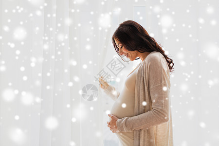 怀孕,母亲,冬天,人们期望的快乐的孕妇,大腹便便的窗户雪图片