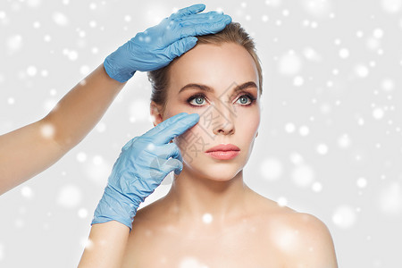 人,美容,整形手术美容外科医生美容师手触摸女人的脸灰色的背景雪图片