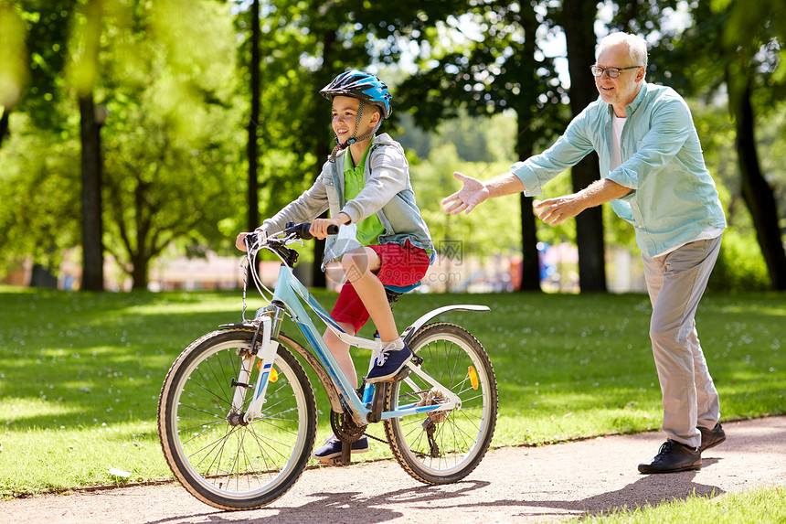家庭,世代,安全人的快乐祖父教男孩如何骑自行车夏季公园图片