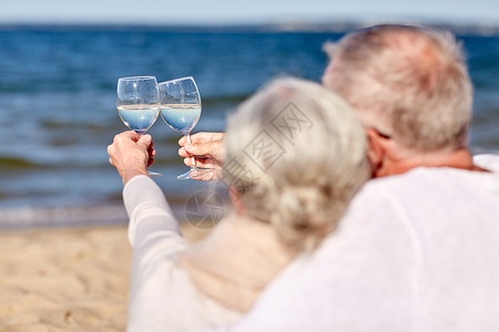 家庭龄假期休闲人的夏日海滩上,幸福的老夫妇碰杯高清图片