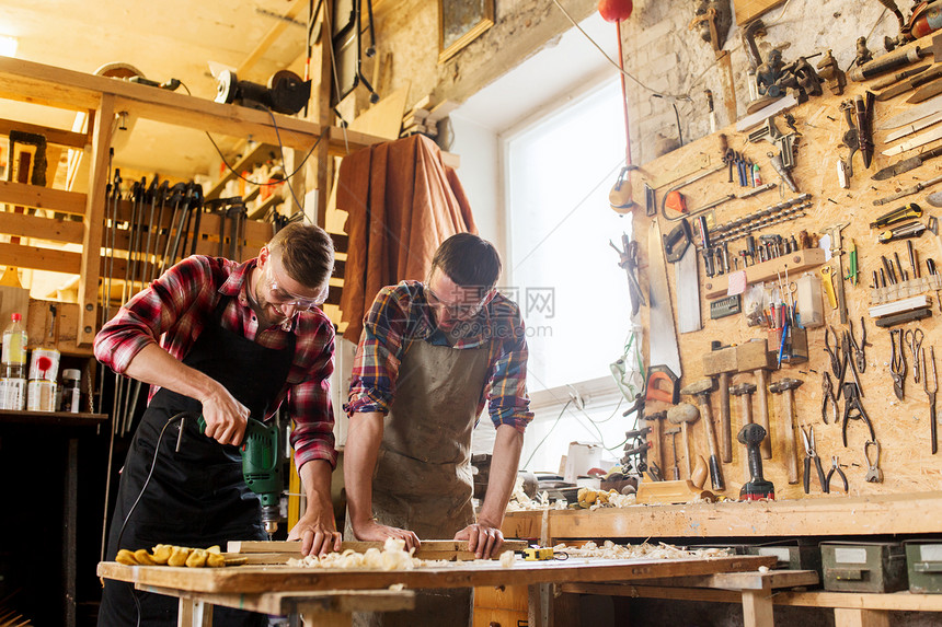 专业,木工,木工人的两个木匠与电钻钻孔木板车间图片