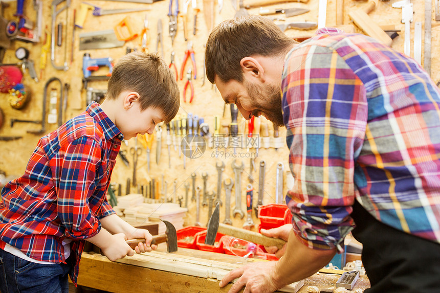 家庭,木工,木工人的父亲小儿子用锤击钉子车间的木板上图片