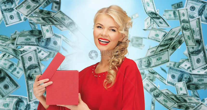 诞节,人,金融假日的微笑的女人穿着红色的衣服,许多礼品盒蓝色的背景金钱雨图片