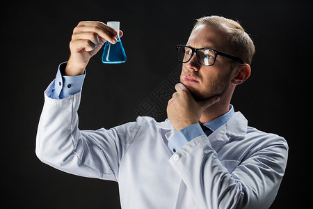 科学,化学,研究人的轻的科学家着黑色背景的化学测试瓶图片