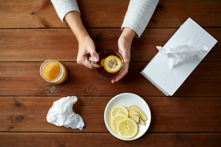 健康,传统医学民族科学生病的女人喝茶与柠檬,蜂蜜生姜纸巾盒木桌上背景图片