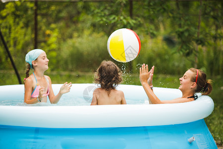 三个女孩蓝色的游泳池里游泳,玩球游泳池里的女孩图片