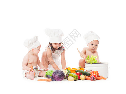 三个孩子玩蔬菜小厨师白色上隔离小厨师饭高清图片