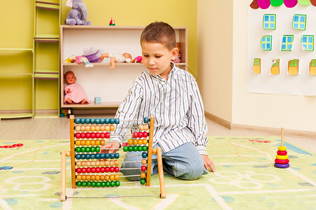 可爱的学龄前儿童男孩玩木色算盘教育游戏背景图片