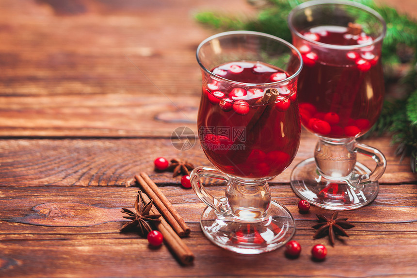 杯带蔓越莓香味肉桂棒的木桌上的覆盖葡萄酒蔓越莓的桑椹酒冬天的饮料图片