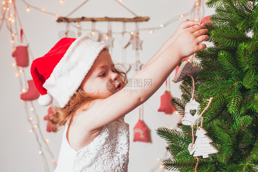 穿着诞老人帽子的漂亮小女孩正装饰诞树诞节的心情图片
