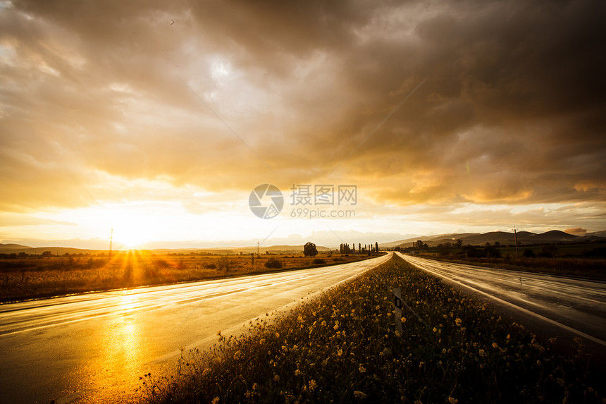 潮湿的道路天空雨后的湿路田野上的日落图片