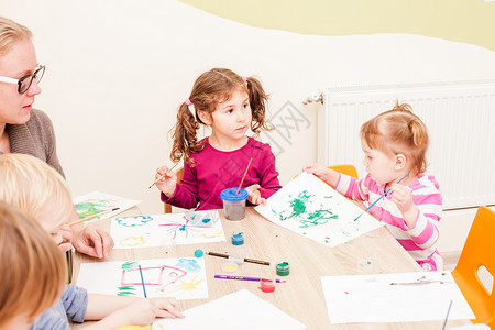 孩子导师正幼儿园用画笔水彩画纸上孩子们正画画图片