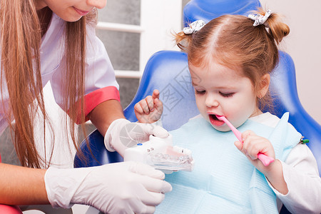 两岁的女孩正牙科办公室里学着用牙刷刷牙牙科办公室的女孩图片