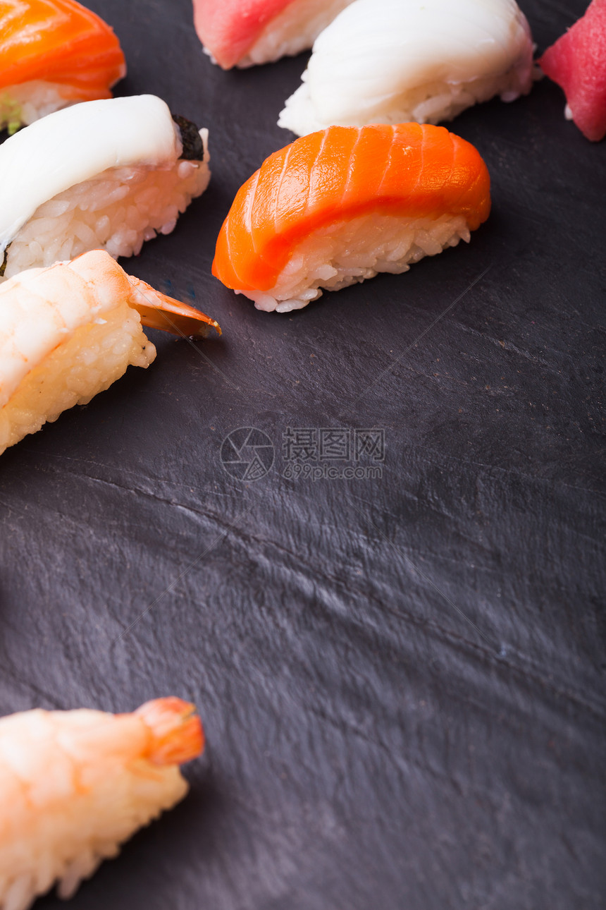 特写四套寿司与鲑鱼,金鱼,扇贝虾黑色背景与图片