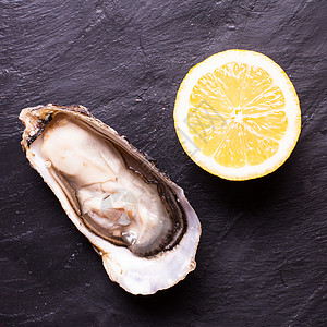 石板背景上的牡蛎肉质柠檬牡蛎加柠檬图片