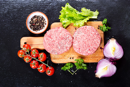 新鲜的生牛肉汉堡汉堡与蔬菜木板上,顶部视图图片